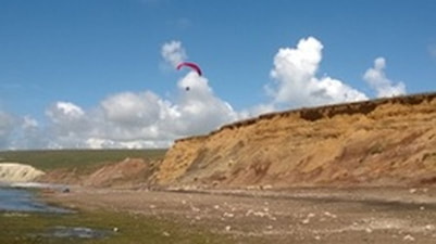 Paraglider over the cliffs at Compton Bay